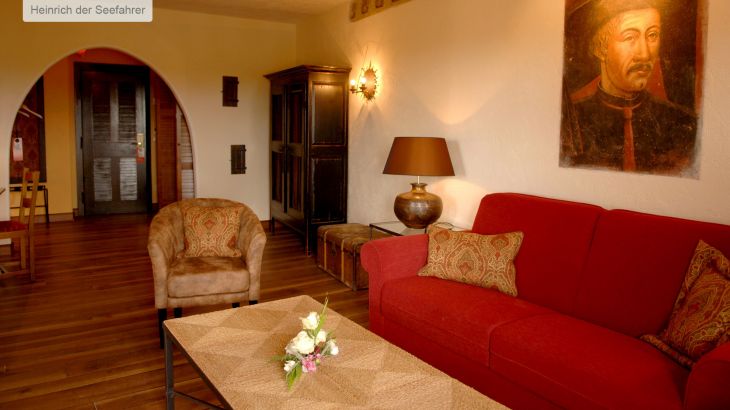 Themensuite Hotel Santa Isabel Heinrich der Seefahrer Wohnzimmer mit Couch, Tisch und Wandbild