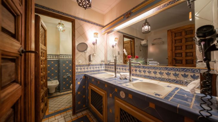Königssuite Badezimmer rechts breiter Spiegel darum blau weiß orange Fliesen links Holztür zur Toilette