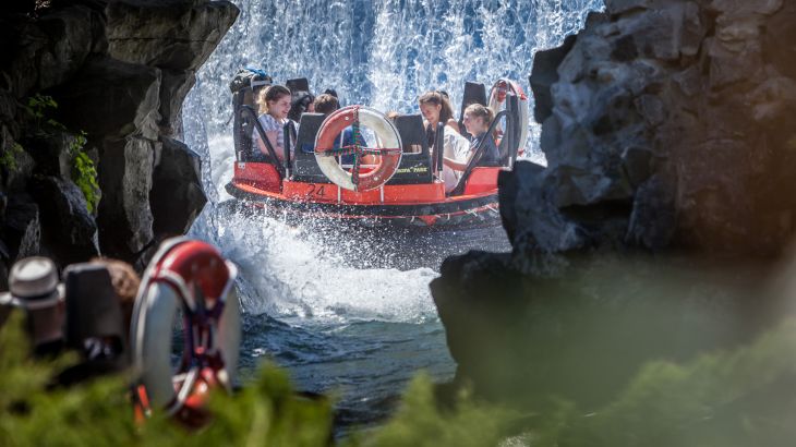 Gruppe fährt im Schlauchboot am Wasserfall entlang