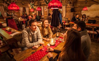 Kleine Gruppen sitzen an den Holztischen in der gemütlichen ERDINGER Hütt'n und verbringen einen geselligen Abend.