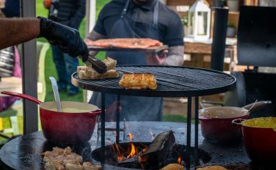 Verschiedenes Essen wird auf einem großen Feuergrill im Europa-Park Erlebnis-Resort zubereitet.