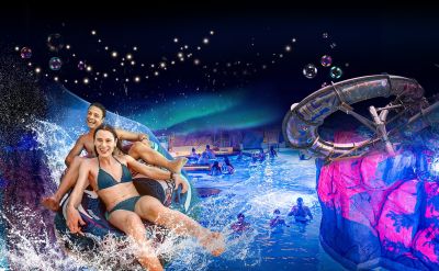 Visuel de la Fête des lumières nordique : l’univers aquatique Rulantica d'Europa-Park Resort et ses illuminations féériques. Au premier plan, deux personnes glissent en riant sur la bouée d’un toboggan.