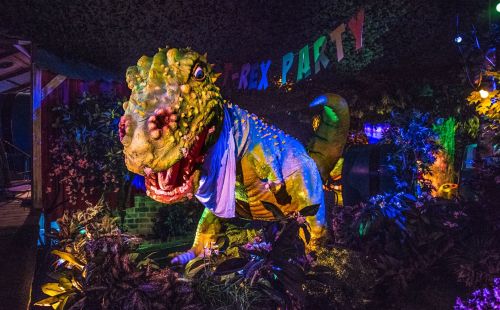 Eine T-Rex Figur, darüber hängt eine Girlande mit der Aufschrift "T-Rex Party"