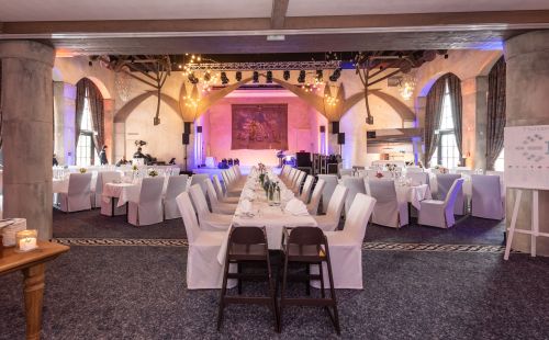 Eingedeckte Tische mit Stuhlhussen in der Eventlocation Vineta