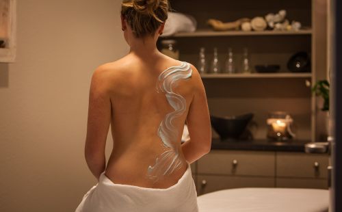 Frau mit Pflegecreme auf dem Rücken