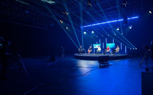 Ein moderator führt 4 Gäste durch eine Diskussion im Livestreaming-Studio