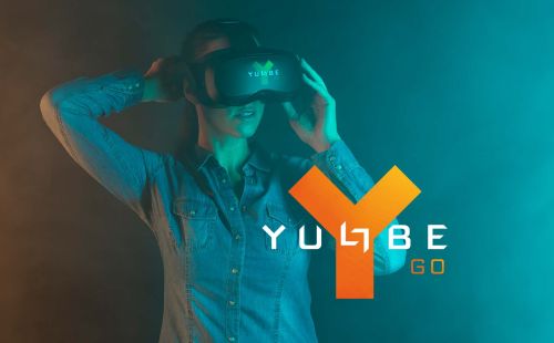 A person puts on the YULLBE GO glasses and prepares for the experience. The YULLBE GO logo is in the foreground.