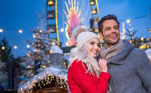 Ein Paar in warmer Kleidung steht vor dem Riesenrad Bellevue