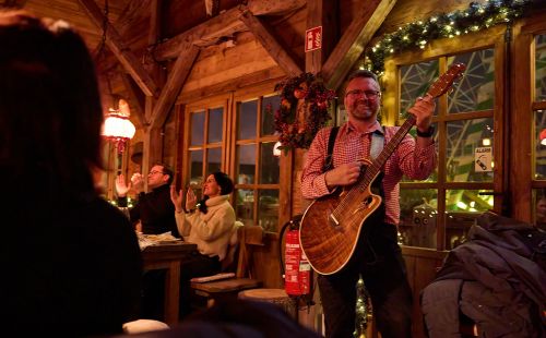 Een muzikant in lederhose speelt tijdens een kerstfeest in de ERDINGER Hütt’n in Europa‑Park.