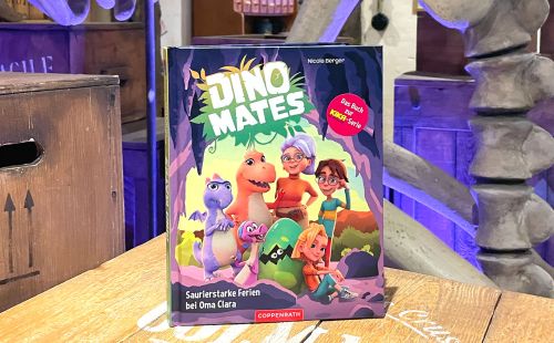 Das Vorlesebuch "DINO MATES – Saurierstarke Ferien bei Oma Clara" auf einem Tisch.