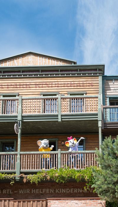 Die Fassade des "Kinderhaus Kleine Helden" und Ed und Edda stehen auf einem Balkon.