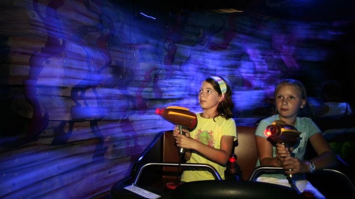 Kinder fahren durch die Gänge von Atlantis, dabei Zielen sie mit der Laserpistole