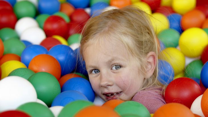 Mädchen versteckt sich im bunten Ballpool