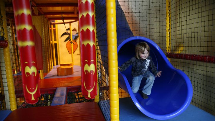 Kind kommt gerade aus einer blauen Rutsche