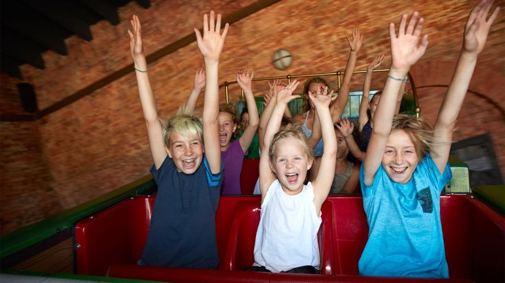 Eine Gruppe Kinder färt im Dancing Dingie und hebt die Arme in die Luft