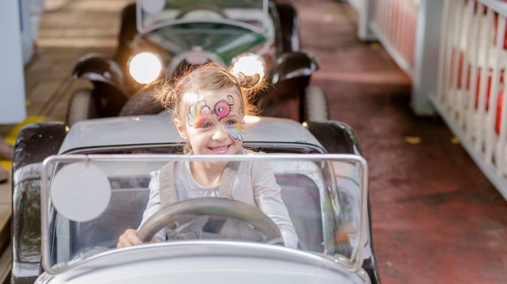 Geschminktes Mädchen im Auto des Lada Autodroms, hinter ihr die Lichter des hinterherfahrenden Waegns