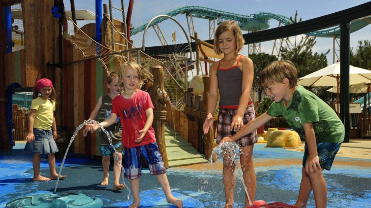 Kinder spielen an kleinen Wasserfontänen