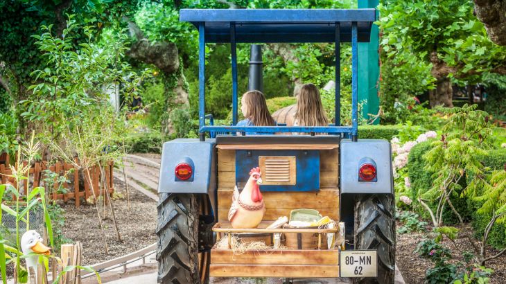 Zwei Mädchen im Traktor auf Old Mac Donald's Farm, hinten sitzt ein Huhn auf dem Traktor