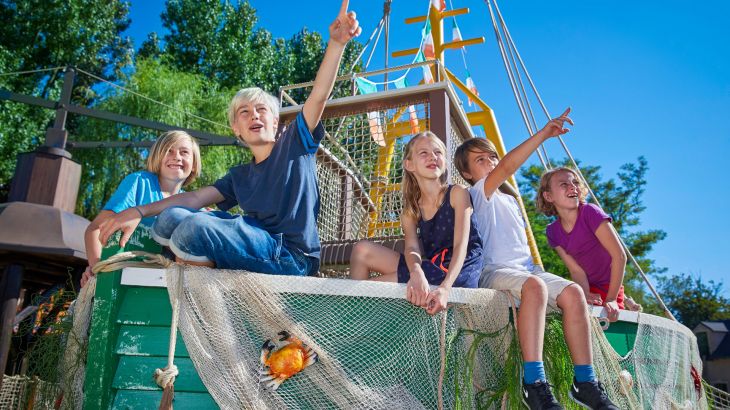 Kinder sitzen auf Paul's Playboat und zeigen in die Luft