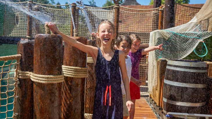 Kinder spielen an Wasserfontänen