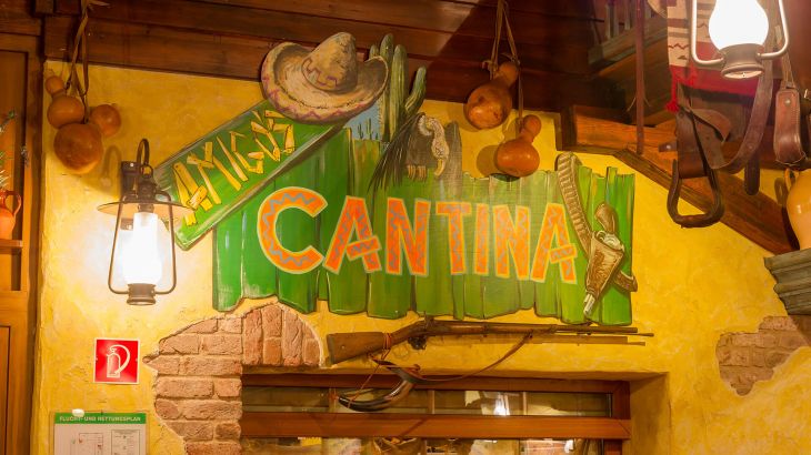 Logo Amigo's Cantina auf der Wand und darunter hängt eine Schrotflinte