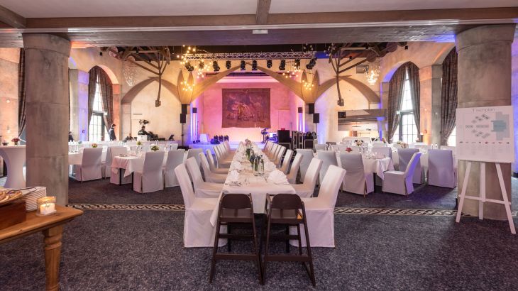 Eingedeckte Tische mit Stuhlhussen in der Eventlocation Vineta
