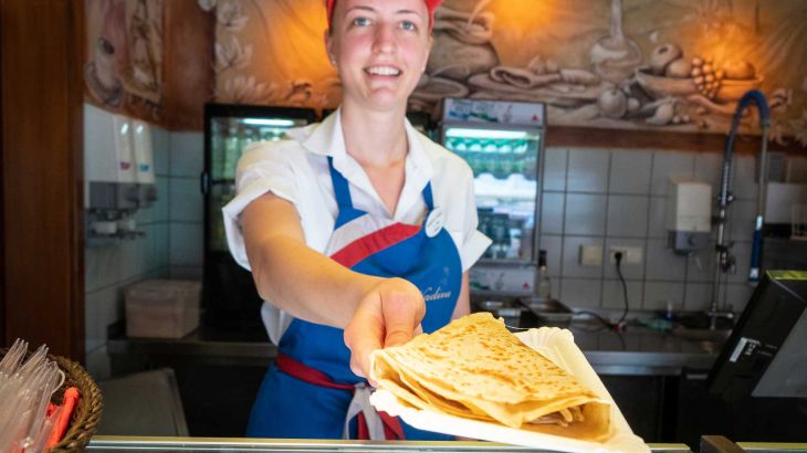 Creperie Nadine Frau überreicht einen Crepe