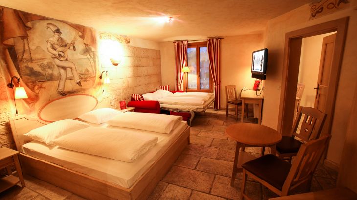 Deluxe-Zimmer Hotel Colosseo zwei Doppelbetten mit Wandgemälde, Fenster und Fernseher
