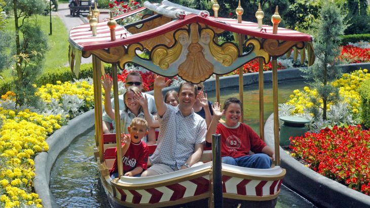 Eine Familie in einem Boot der Elfenfahrt winkt in die Kamer