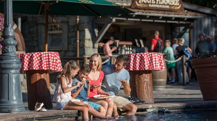 Flammkuchenstand im Sommer mit einer Familie die Ihre Beine im Wasser baumeln lässt