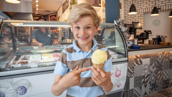 Ein glücklicher Junge mit einem Großen Eis in der Hand steht vor der Is Huset Eistheke