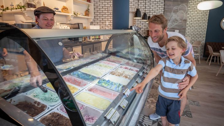 Ein Vater sucht mit seinem Sohn eine Eissorte an der Is Huset Eistheke aus