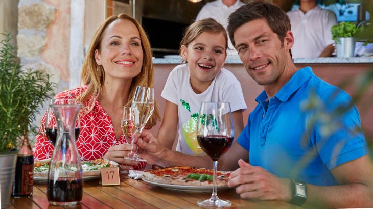 Eine Familie isst Pizza in der Gartenwirtschaft der Pizzeria la Romantica