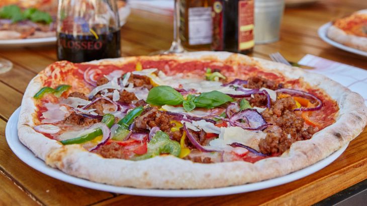 Eine Pizza Bolognese mit frischem Basilikum garniert