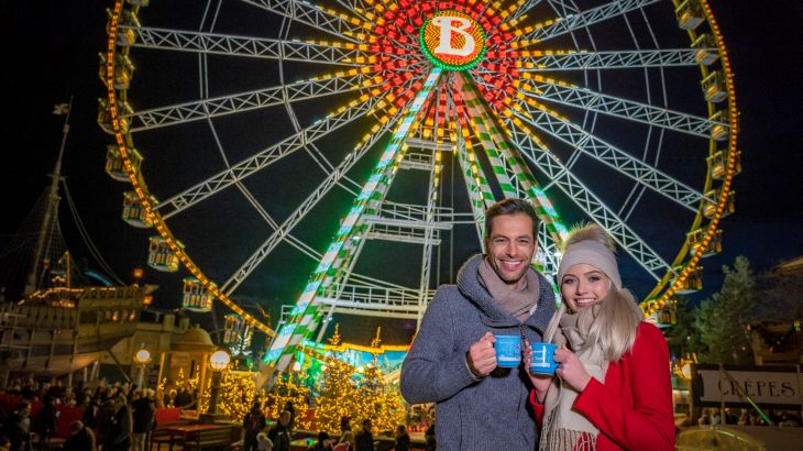 Paar vor dem beleuchteten Riesenrad bei Nacht