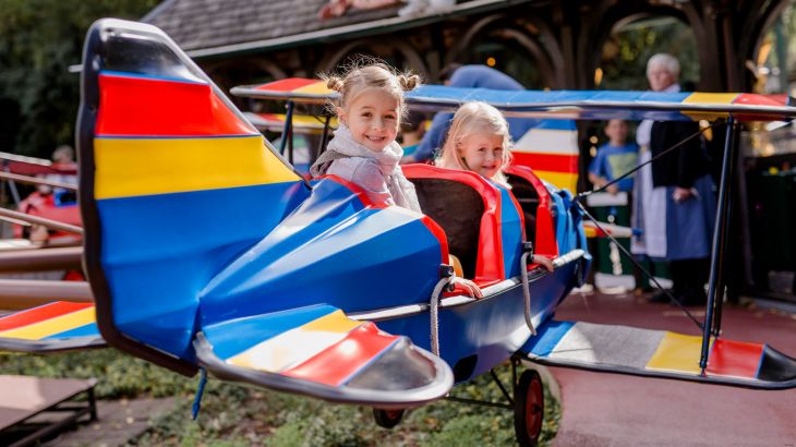 Kinder sitzen in blauem Flugzeug des Roten Barons