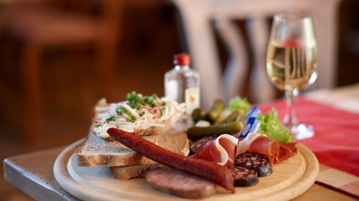 Vesperbrett mit Brot und verschiedenen Wurstsorten dazu einen Schnaps