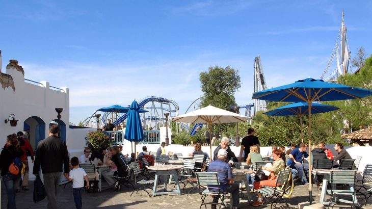 Im Außenbereich der Taverna sitzen Gäste unter Sonnenschirmen