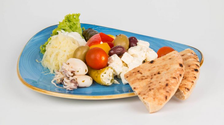 Grichischer Salat mit Fladenbrot auf einem blauen Teller