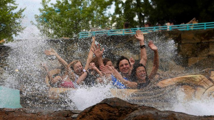 Besucher bei der Abfahrt der Wildwasserbahn, sie heben die Hände in die Luft