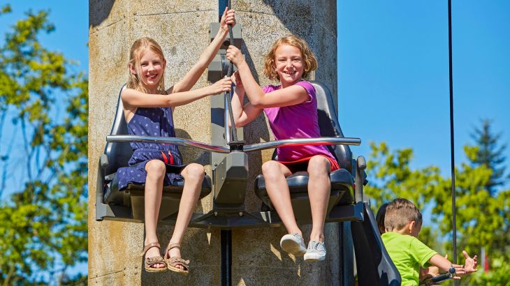 Kinder sitzen in einem Sitz und ziehen sich am Tower Tow hoch