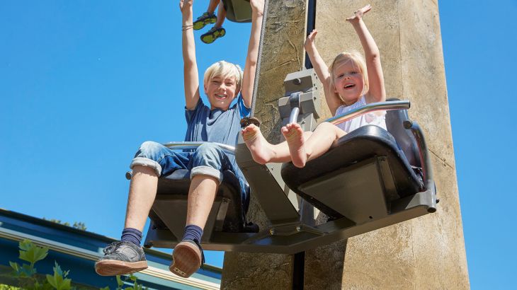 Kinder im Sitz des Tower Tows, sie heben die Hände in die Luft