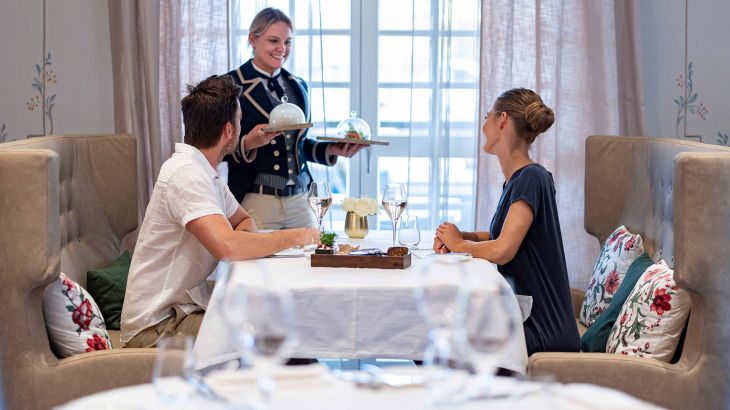 Ein Paar sitzt zusammen und eine Bedienung bring die exclusiven Vorspeisen an den Tisch