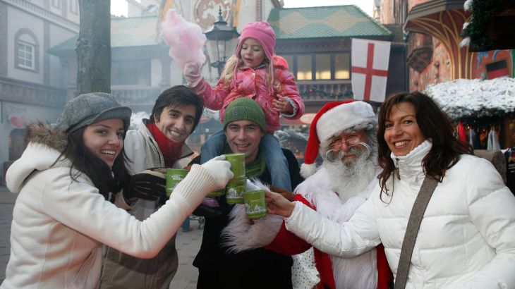 Gäste stehen mit dem Weihnachtsmann auf dem Weihnachtsmarkt zusammen