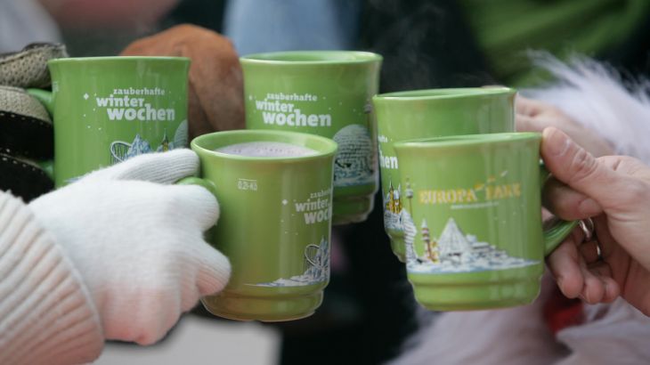 Grüne Tassen vom Weihnachtsmarkt mit denen angestoßen wird