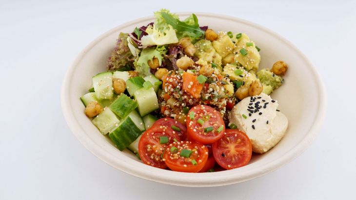 Eine Salat Bowl mit Tomaten, Gurken, Chinoa, Blattsalat und Hummus