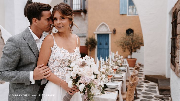 Junges Brautpaar vor dekorierten Tisch im griechischen Themenbereich