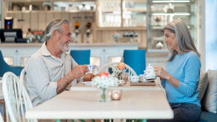 Ein älteres Ehepaar sitzt mit Kaffee an einem Tisch
