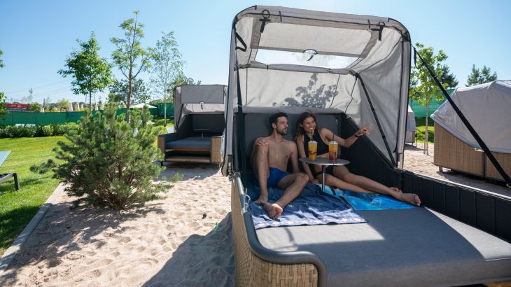 Ein Paar liegt mit Cocktails auf einer Strand Insel im Außenbereich von Rulantica