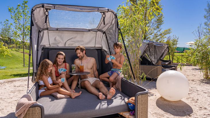 Ein Familie liegt auf einer Strand Insel im Außenbereich von Rulantica und spielt Karten